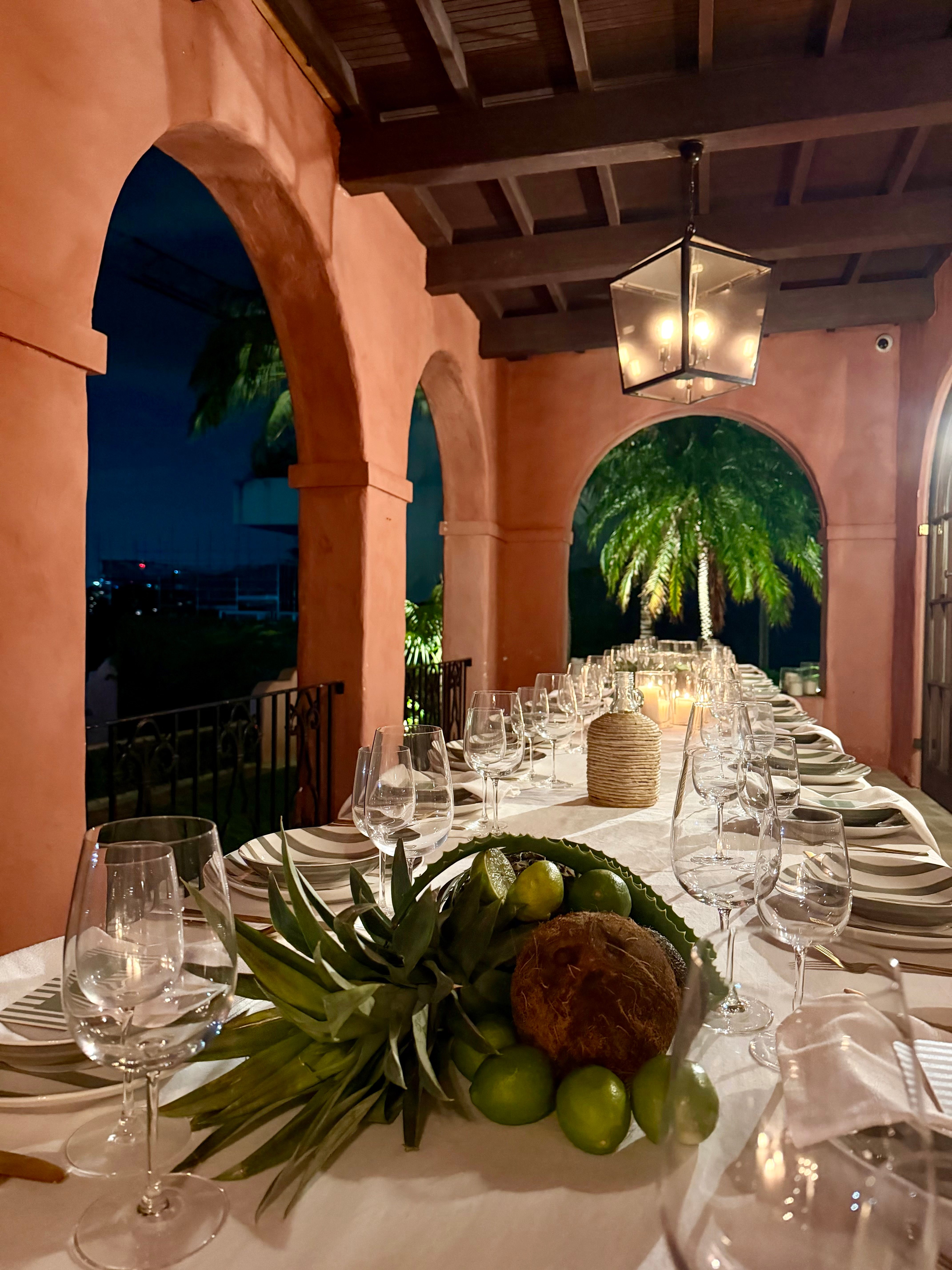 Loggia dinner with white linens, striped plates, pineapple and lime centerpieces at blue hour