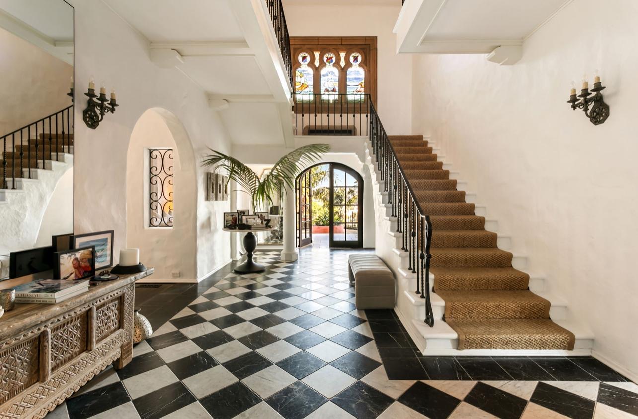 Grand foyer with checkered marble, sisal staircase runner and stained glass windows