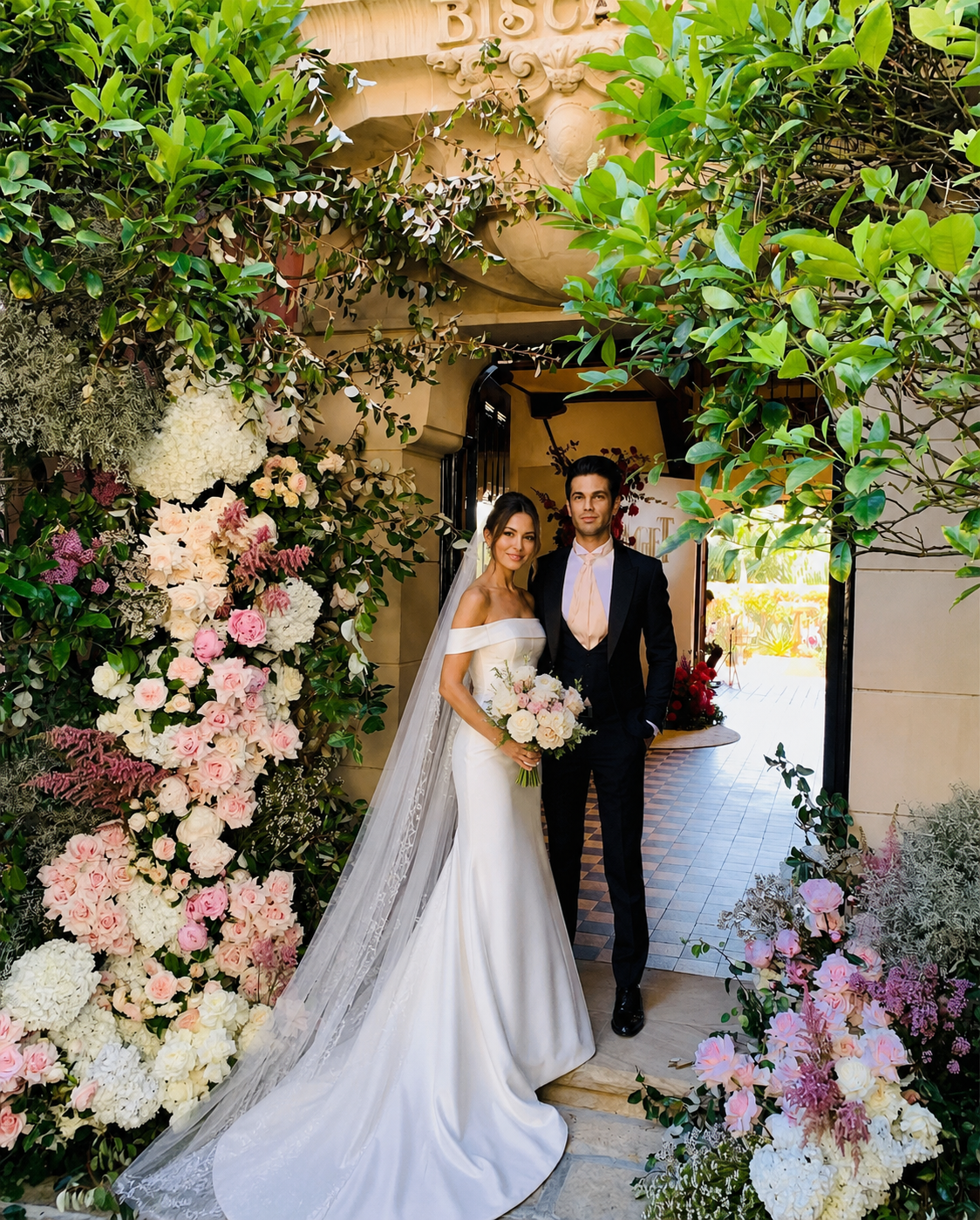 Wedding couple beneath floral arch at Villa Biscaya